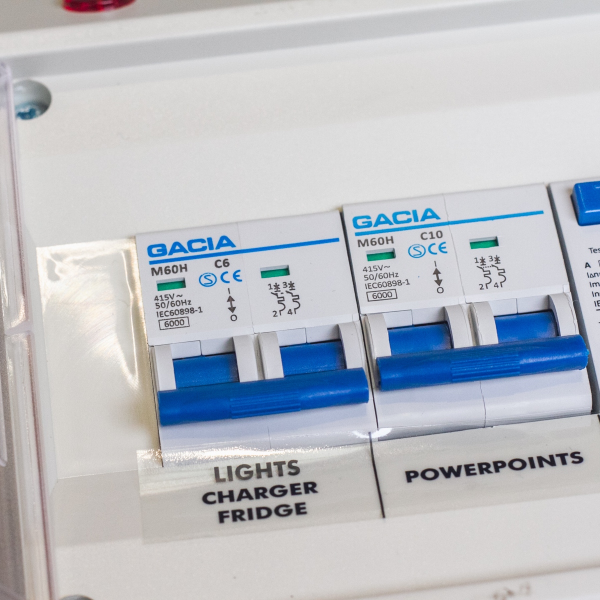 Close-up of a Consumer Unit - 25A RCD‚ 10A & 6A double pole MCB labeled "Lights Charger Fridge" and "Powerpoints" with blue switches, brand "Gacia".
