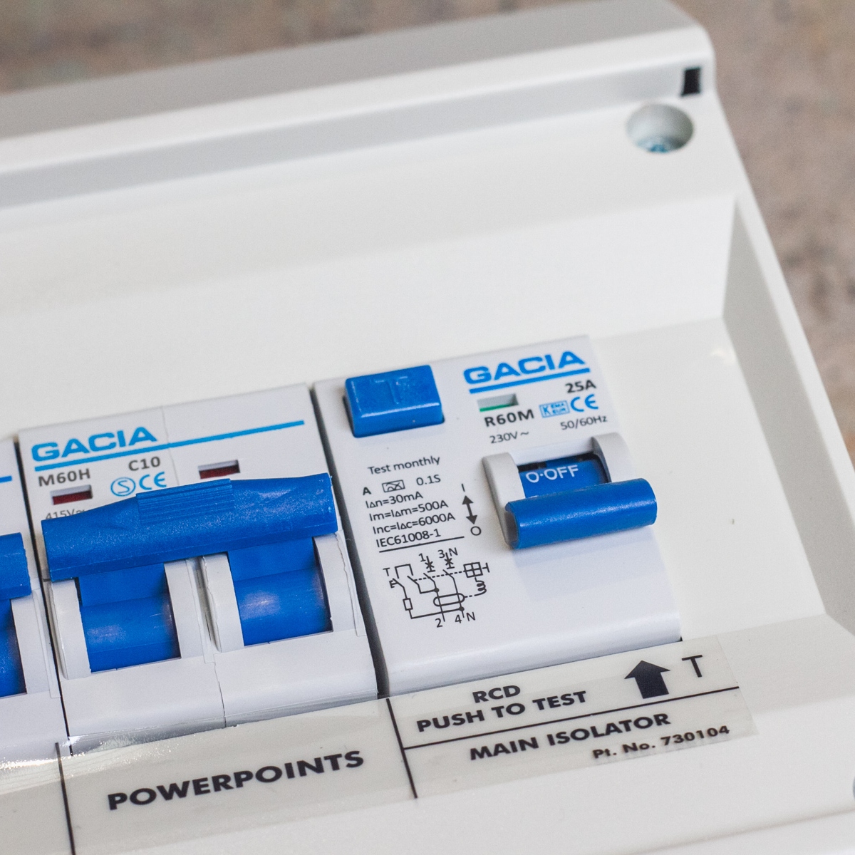 Close-up of a Consumer Unit - 25A RCD‚ 10A & 6A double pole MCB with blue switches labeled PowerPoints, Main Isolator, and RCD Push to Test.