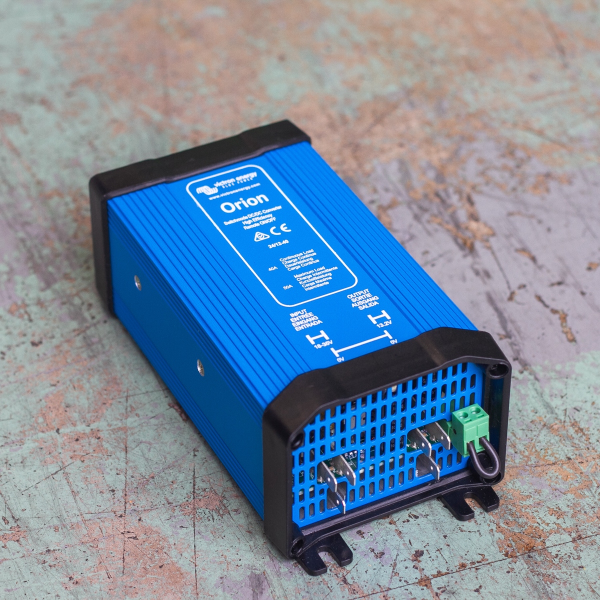 The Victron Orion 24/12-40 DC-DC Converter - 24V to 12V 40A Non-isolated Converter with wiring connections is displayed on a textured surface.