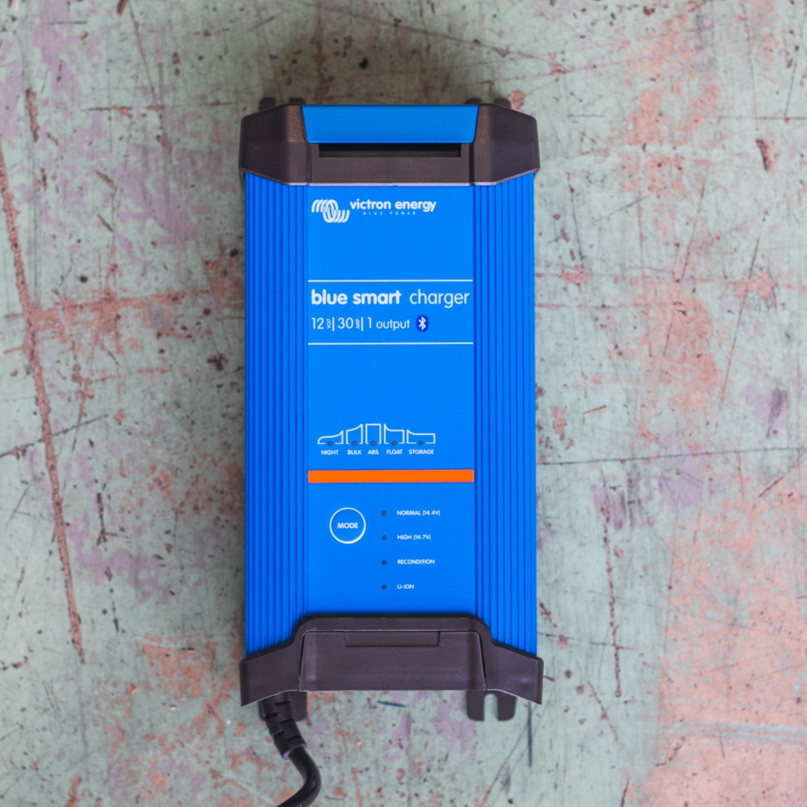 A blue Victron Battery Charger 12/30 - Indoor (IP22) Blue Smart - 1 Output rests on a worn, painted surface.