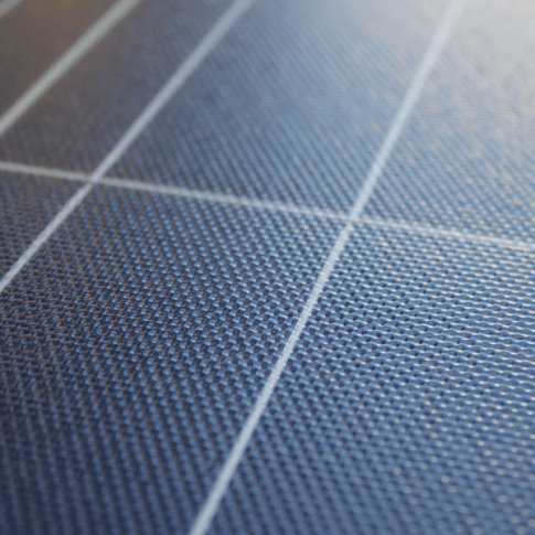 Close-up of a blue solar panel surface, showing its texture and intersecting white grid lines.