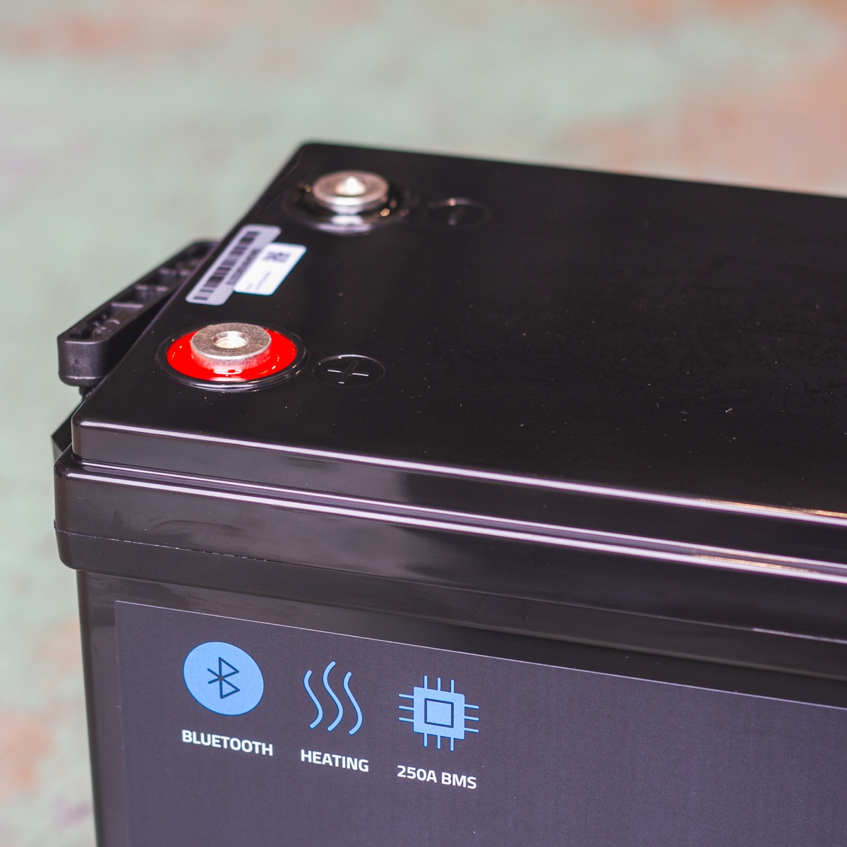 Close-up of a black battery with Bluetooth, heating, and 250A BMS symbols on its side; this impressive unit is the Fogstar Drift 230Ah - 12V lithium leisure battery.