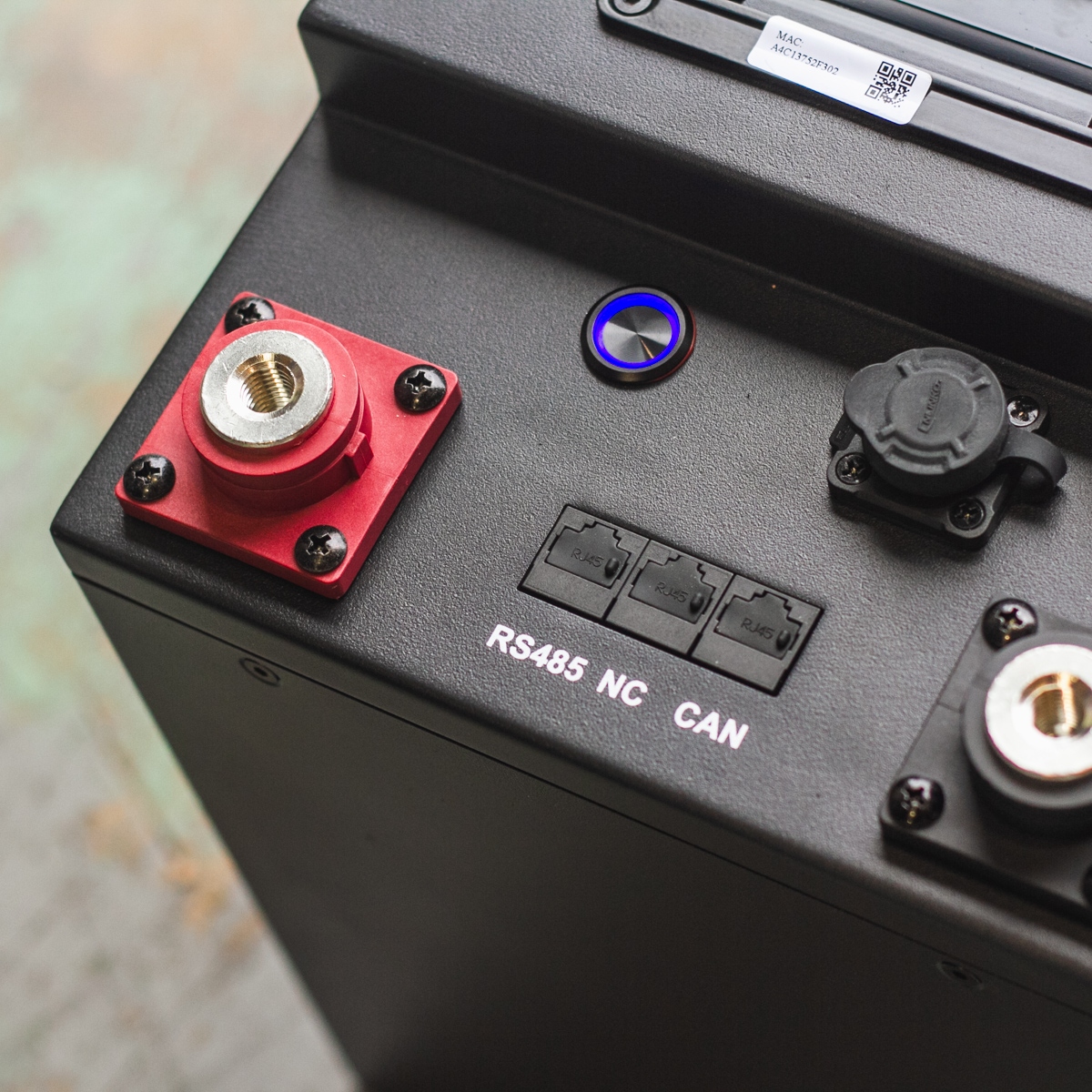 Close-up of black electronic equipment from the Fogstar Drift PRO 300Ah - 12V lithium leisure battery, featuring labeled ports and a red connector, highlighting RS485, NC, and CAN ports.