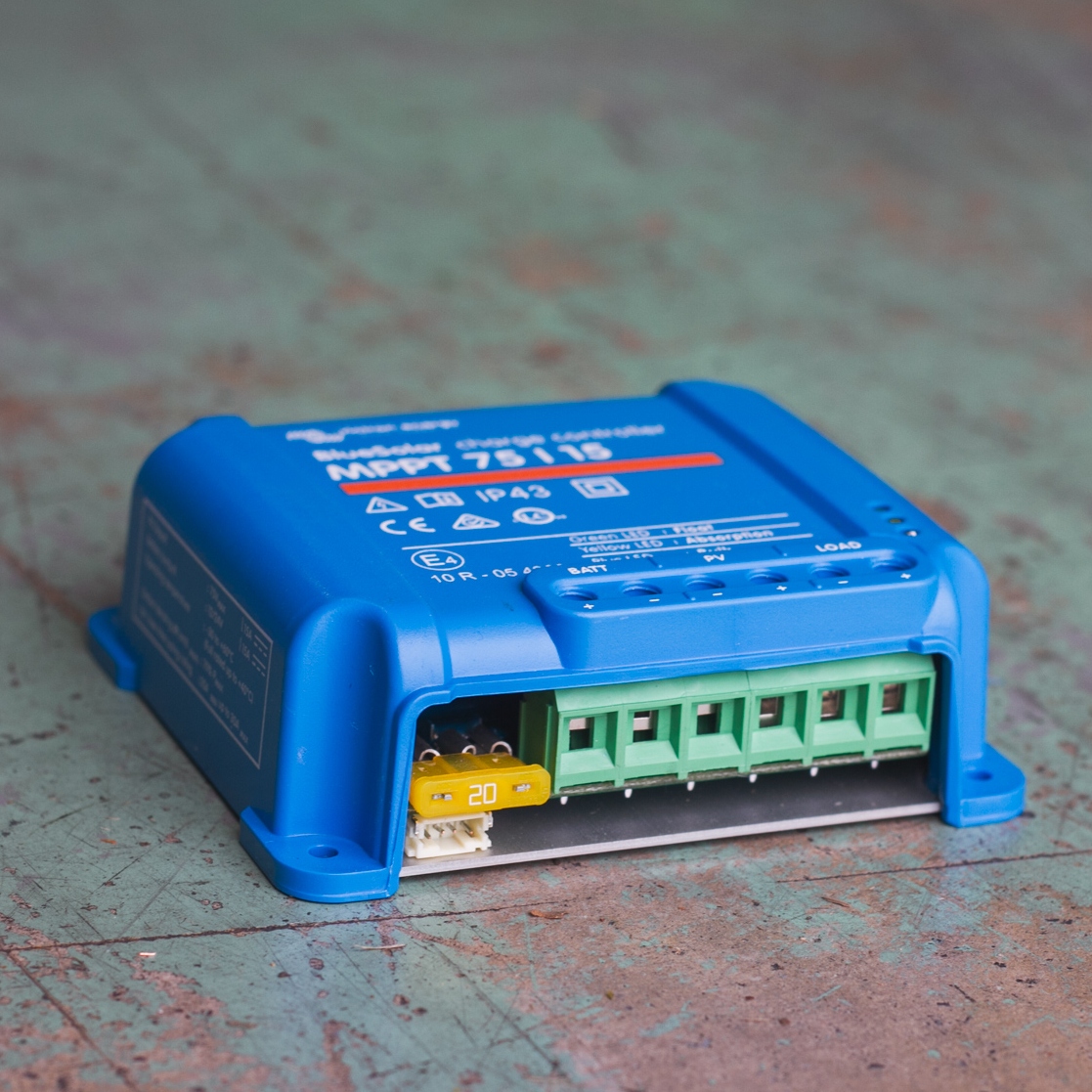 The Victron MPPT 75/15 - BlueSolar Charge Controller features multiple green connection terminals, all set against a weathered blue surface.