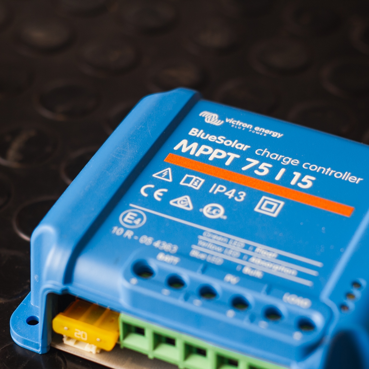 Close-up of a Victron MPPT 75/15 - BlueSolar Charge Controller in blue, pictured on a sleek black surface.
