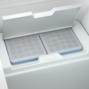 Two grey ice packs inside a white cooler with the lid partially open.