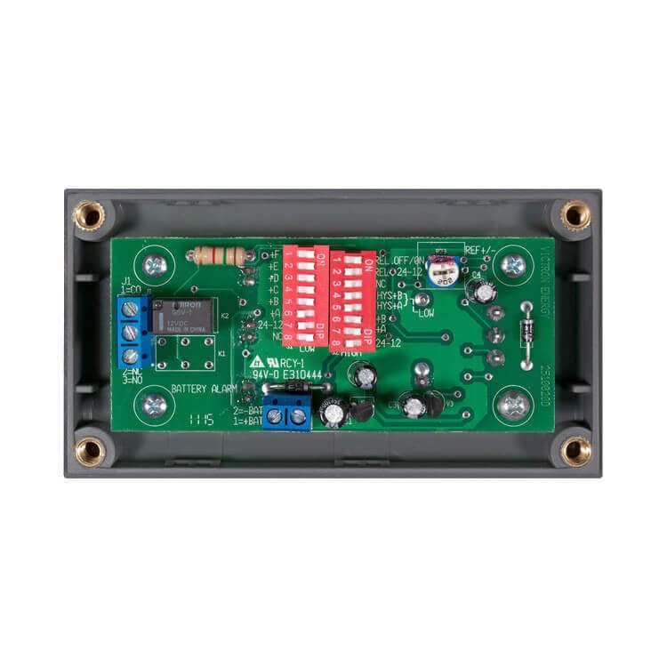 A green electronic circuit board with multiple red switches, capacitors, and resistors in a grey rectangular casing is part of the Victron Energy Battery Alarm GX.