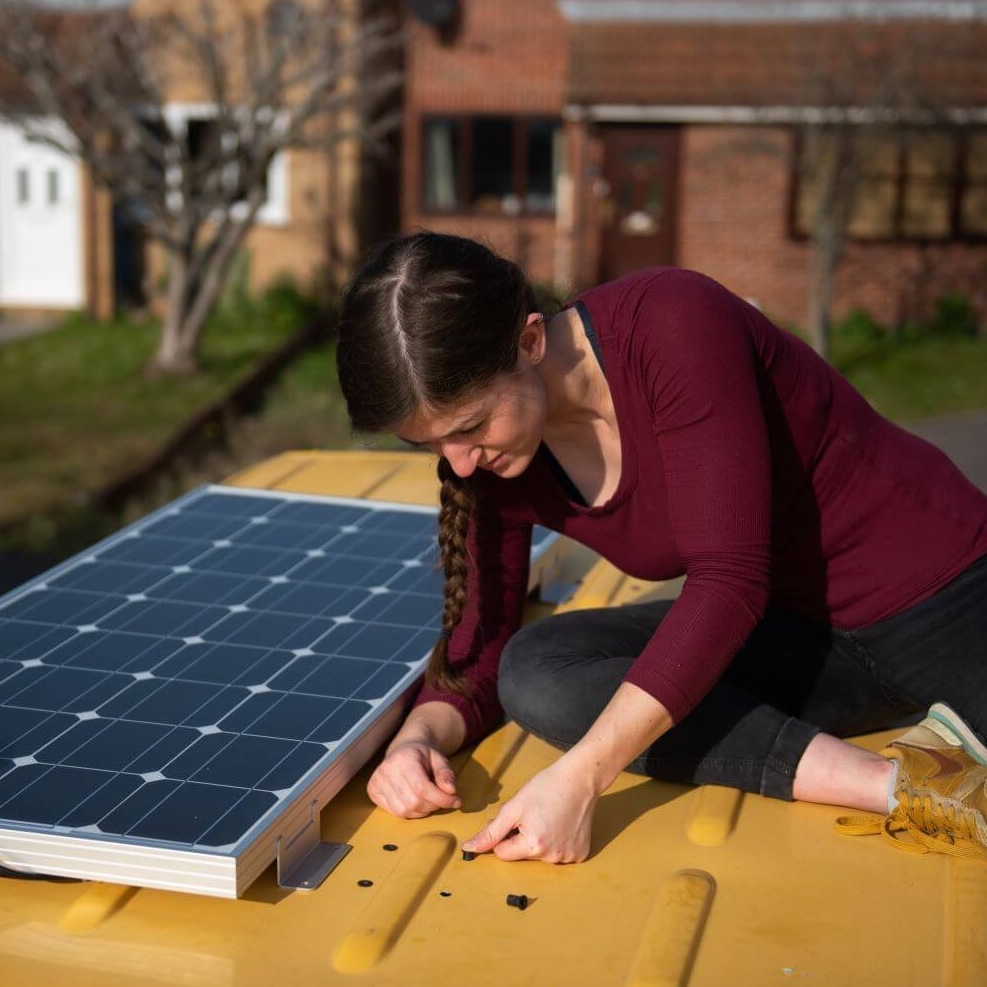 woman installing rubber well nuts on the roof of a campervan installing solar panels