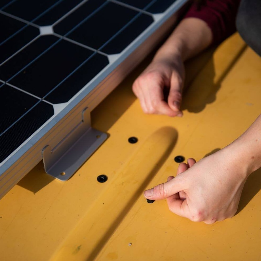woman installing well nuts on the roof of a campervan installing solar panels