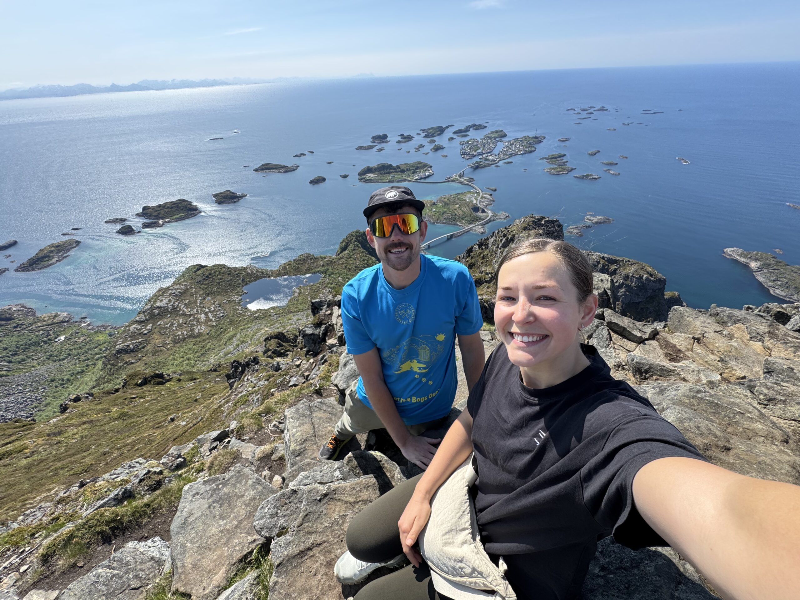 Jack and LJ on a sunny day on top of a cliff overlooking a calm sea