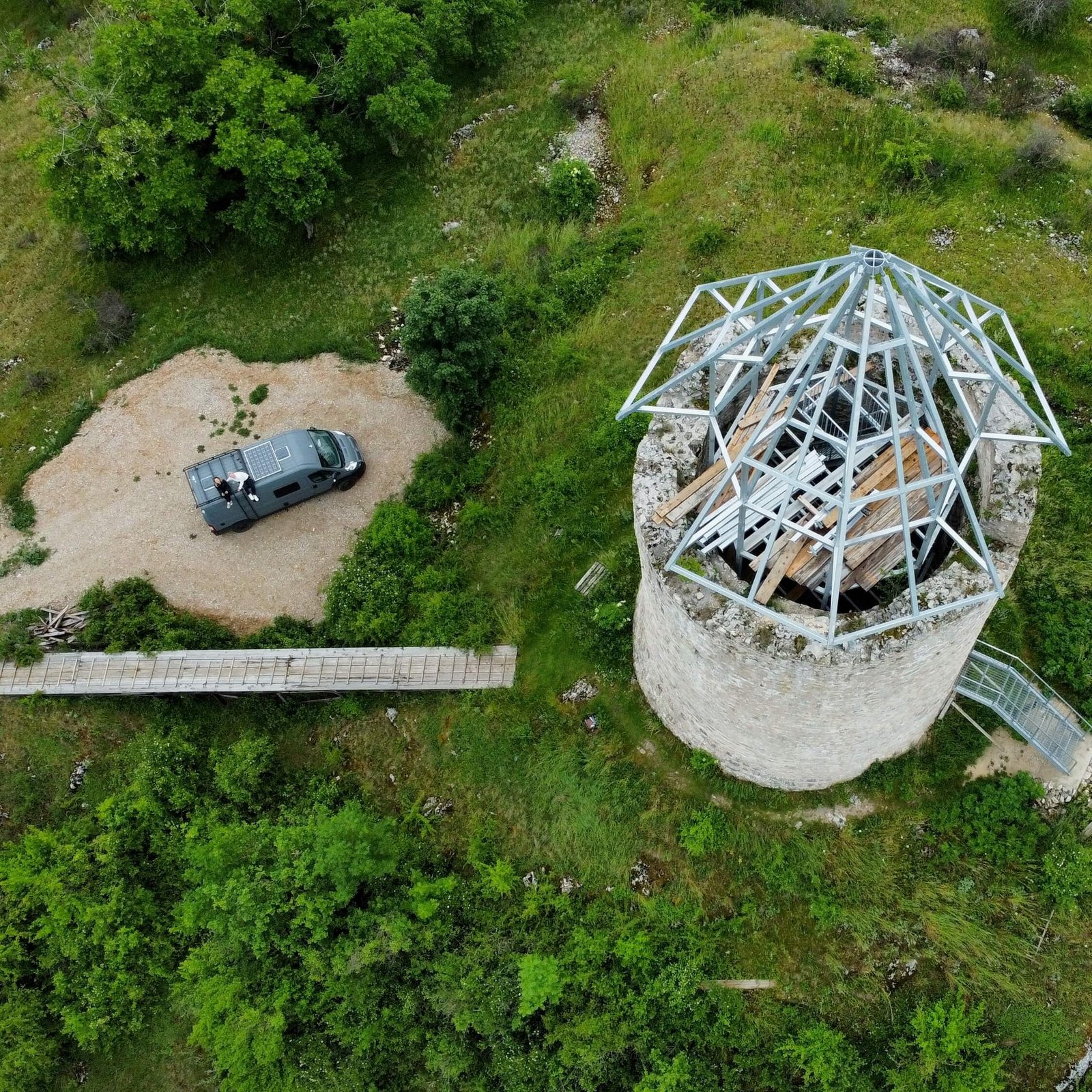A drone shot of Becky and Millies van parked up next to a tower with a visible roof structure