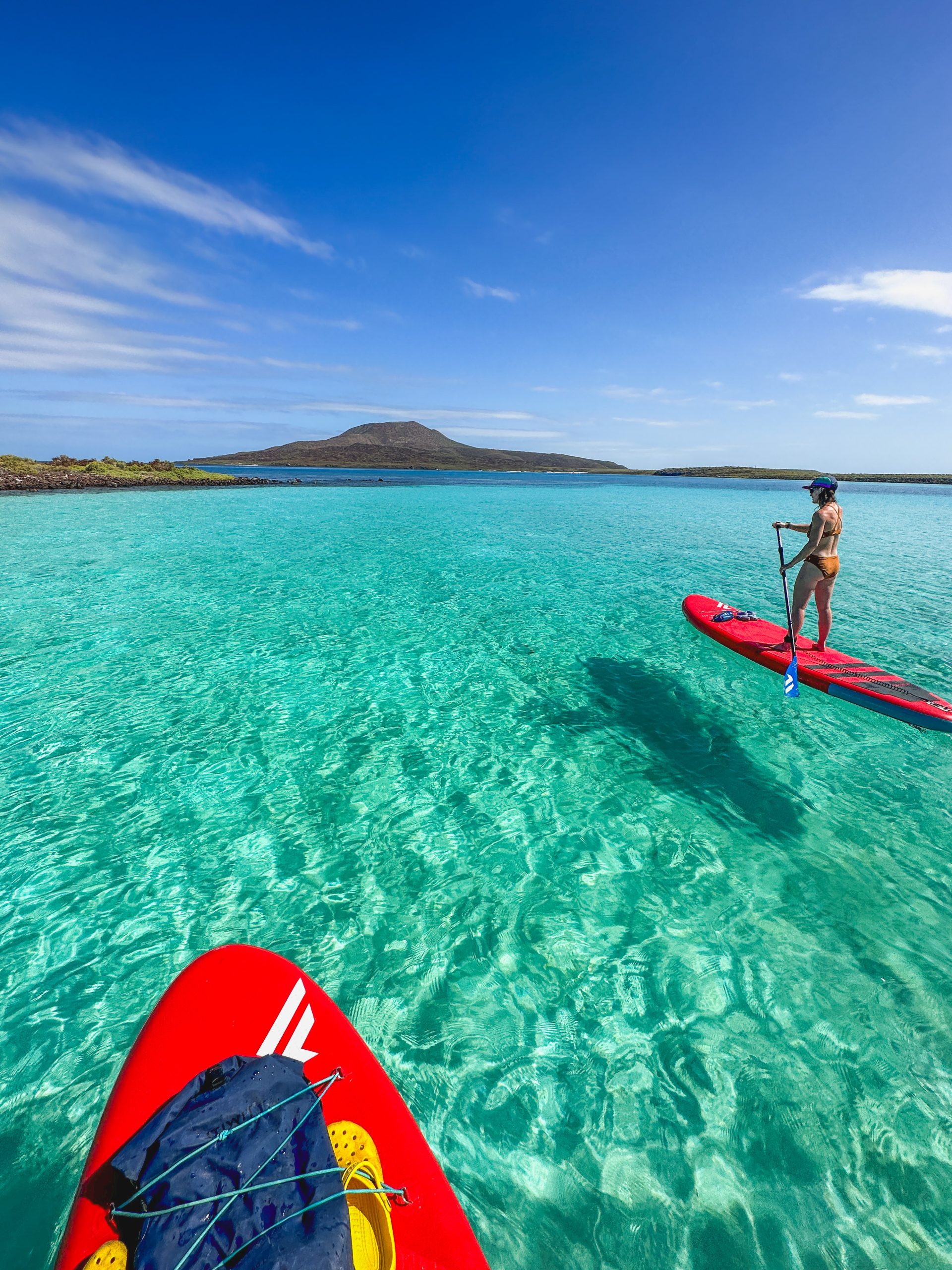 a woman on a red SUP in crystal clear water