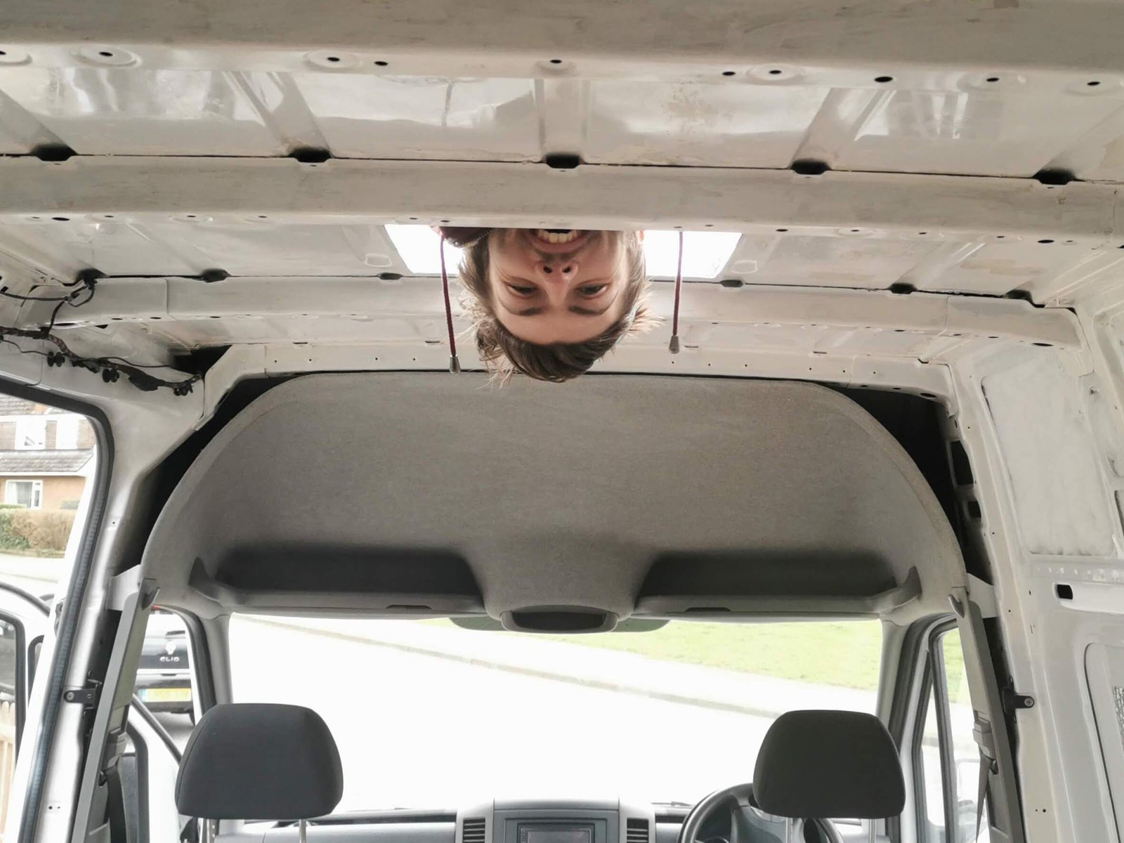Dan lying on the roof of his van looking through a cutout into the van