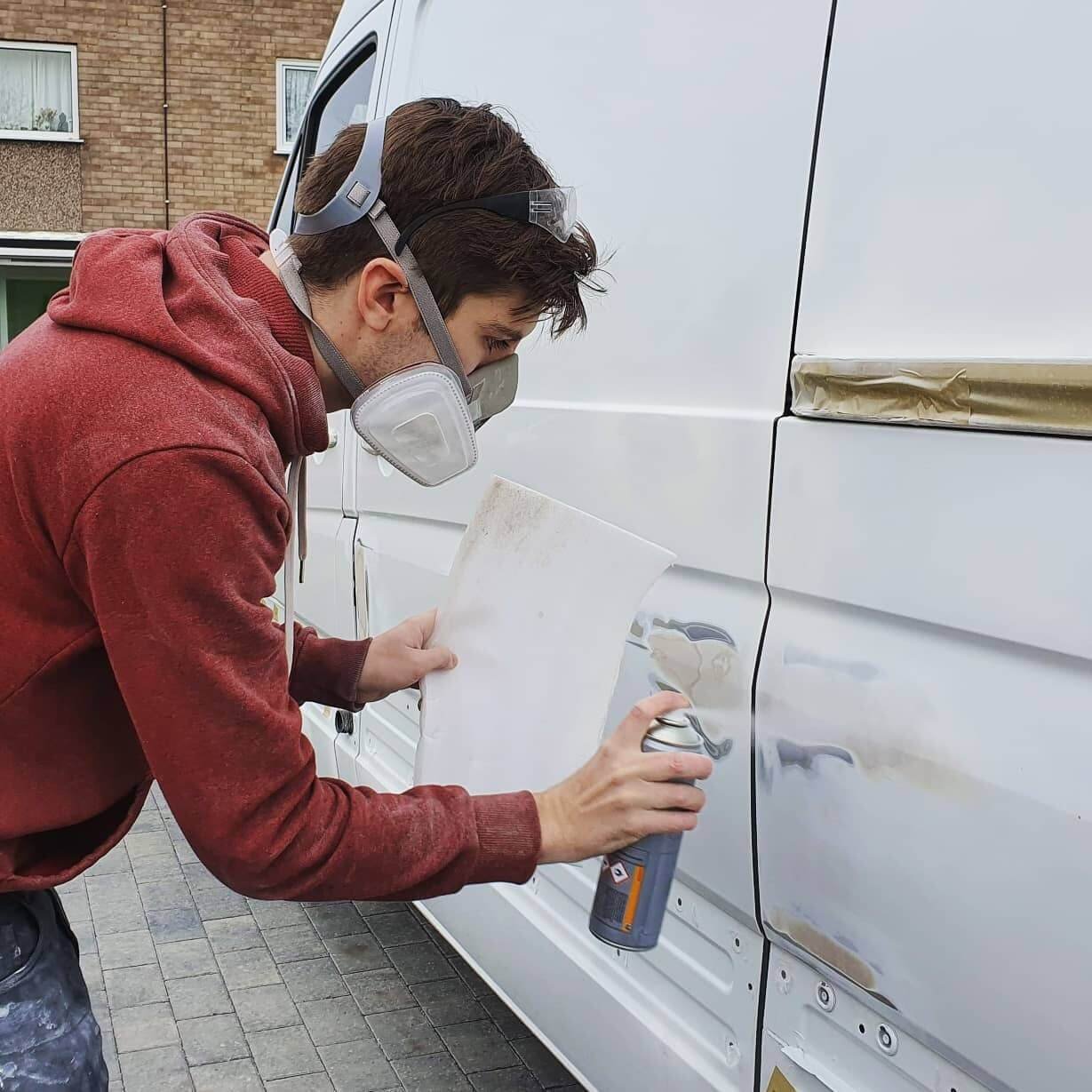 Dan wearing a full dust mask whilst spray painting the exterior of his van