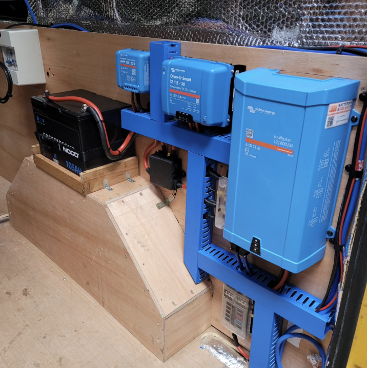 Huey's electrical Victron set up in his van with a 105Ah lithium battery on top of the wheel arch cover